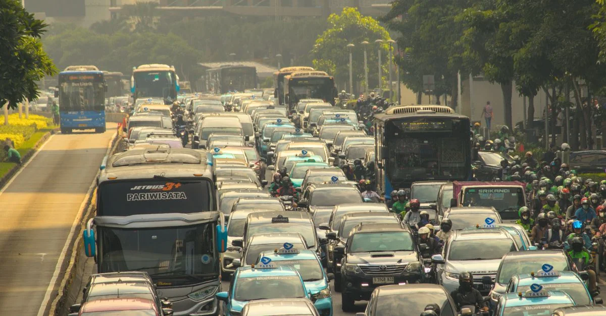 Scène de trafic pare-chocs contre pare-chocs capturant une rue de ville encombrée avec des bus, des voitures et des motos.