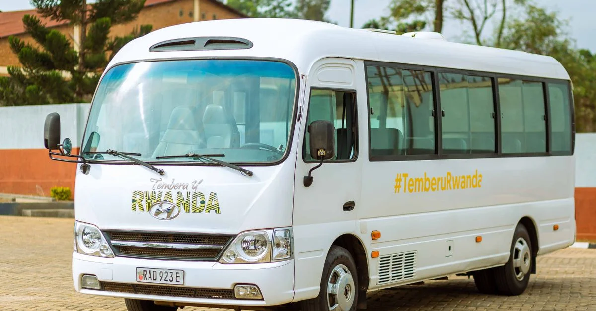 Un autocar blanc promouvant TemberuRwanda, stationné à l'extérieur par une journée ensoleillée.