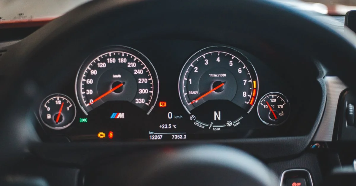 Gros plan sur l'affichage du tableau de bord d'une voiture de luxe avec des instruments lumineux et un compteur de vitesse.