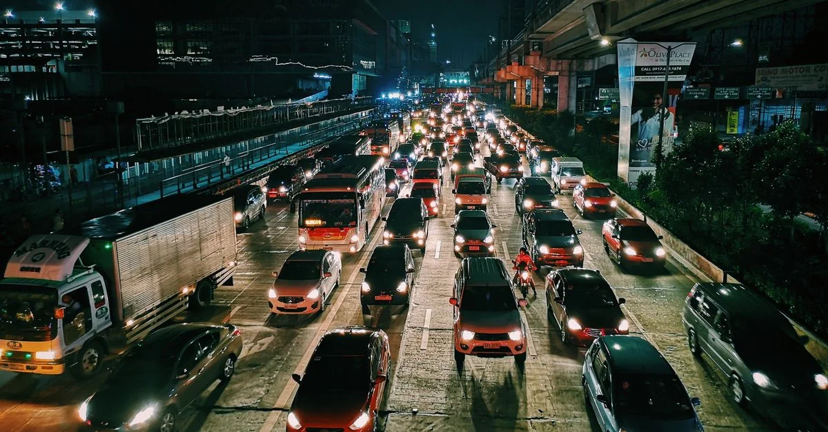 Une autoroute urbaine animée remplie de voitures et de bus la nuit, montrant la vie citadine et les transports.