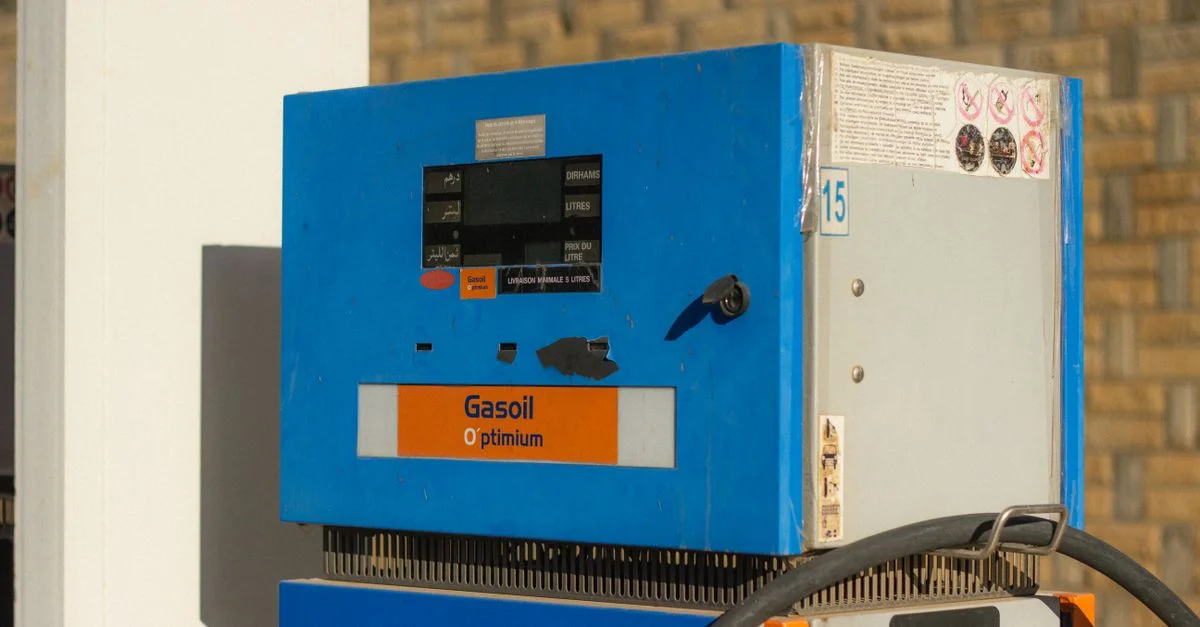 Gros plan sur une pompe à essence vintage avec l'étiquette 'Gasoil Optimum' en bleu et orange.