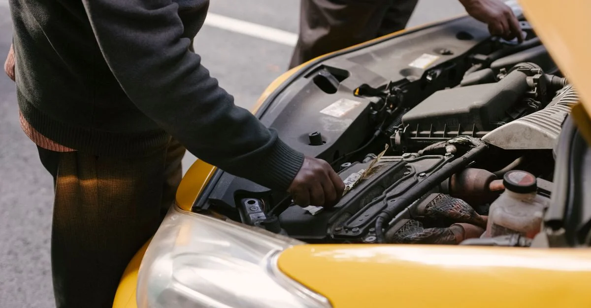 Deux mécaniciens examinant et réparant le moteur d'un taxi jaune sur la route.