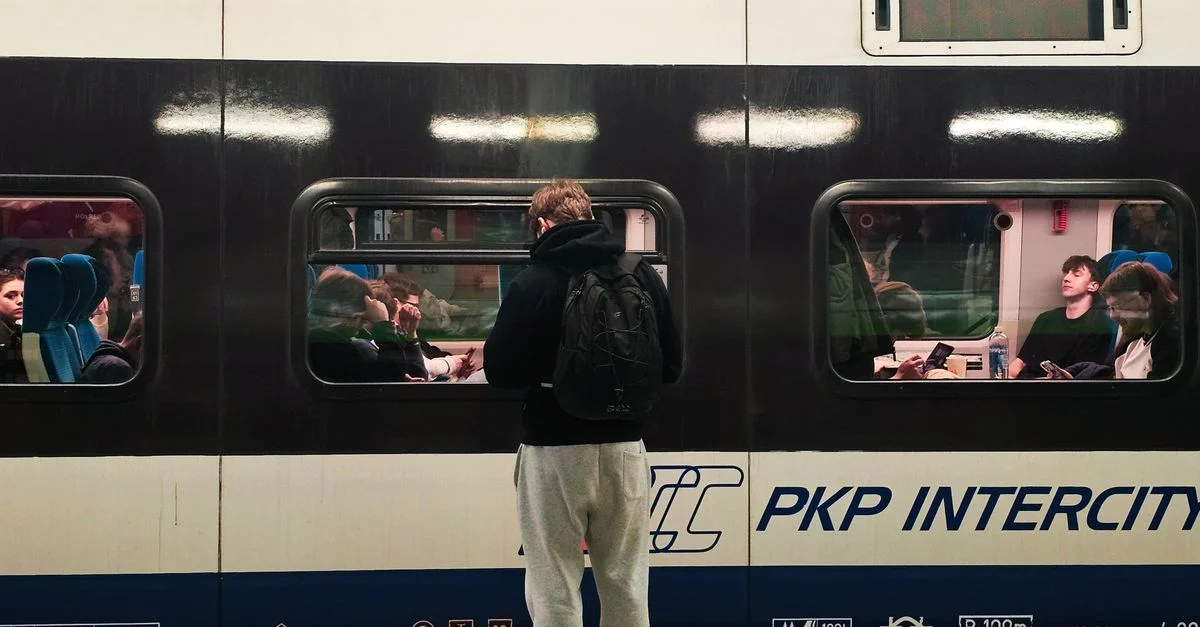 Scène animée à la gare de Wrocław, avec des passagers à bord d'un train Intercity de la PKP et un voyageur attendant sur le quai.