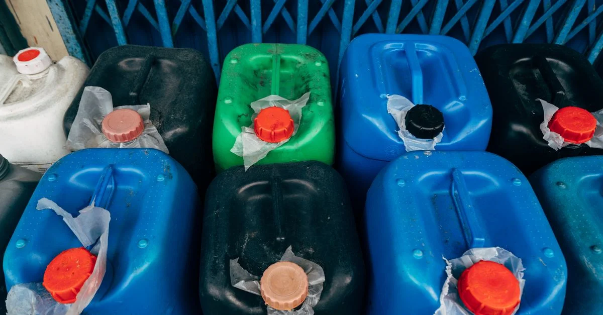 Vue de dessus de divers bidons en plastique colorés utilisés pour le stockage industriel, avec des bouchons rouges.