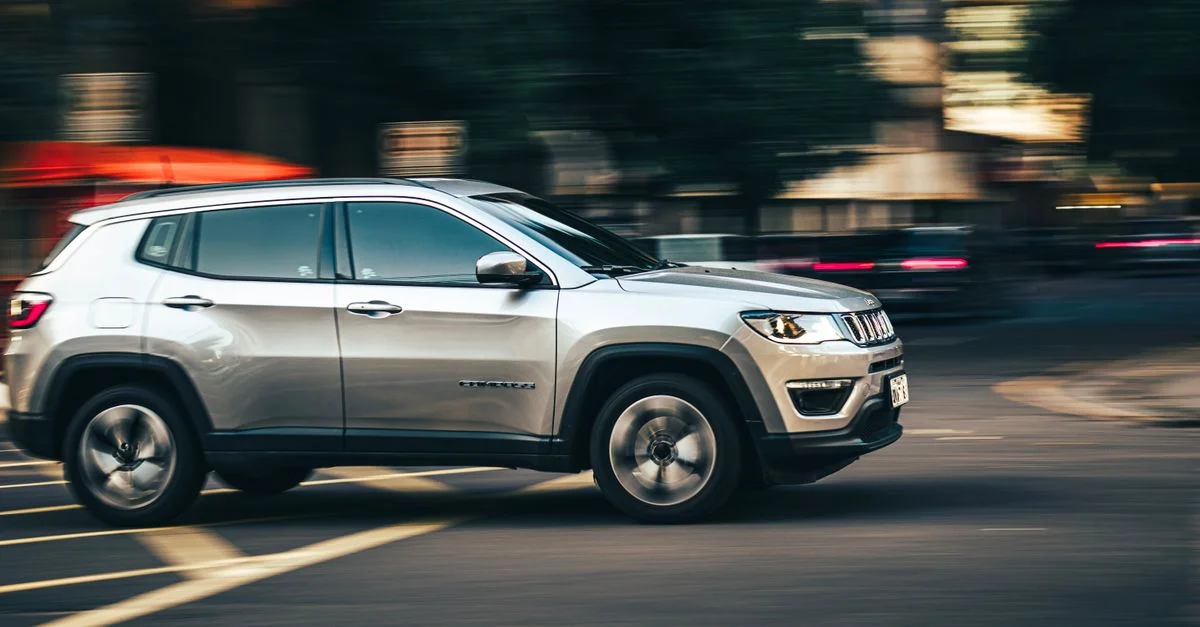Vue latérale dynamique d'un SUV argenté filant en centre-ville, capturant le mouvement urbain.