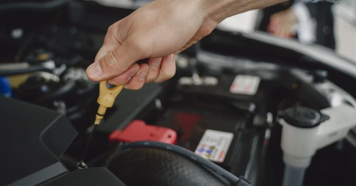 Main vérifiant la jauge à huile dans le moteur d'une voiture pour l'entretien et le diagnostic.