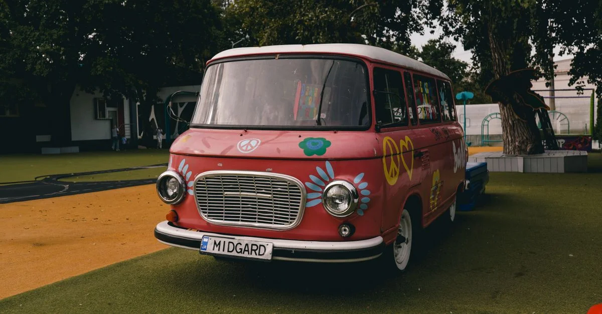 Un minibus rose vintage orné d'œuvres d'art hippie garé dans un parc extérieur verdoyant à Kiev, Ukraine.