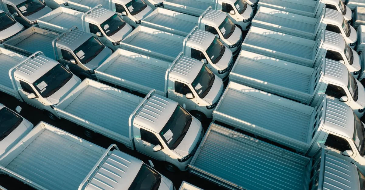 Vue aérienne de camionnettes blanches garées en rangées, mettant l'accent sur la symétrie et le style industriel.