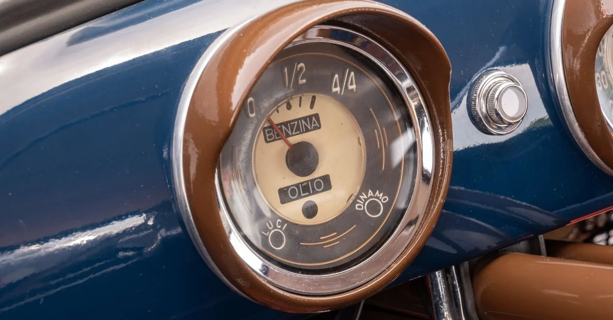 Gros plan sur le tableau de bord d'une voiture rétro mettant en valeur une jauge classique de carburant et d'huile.