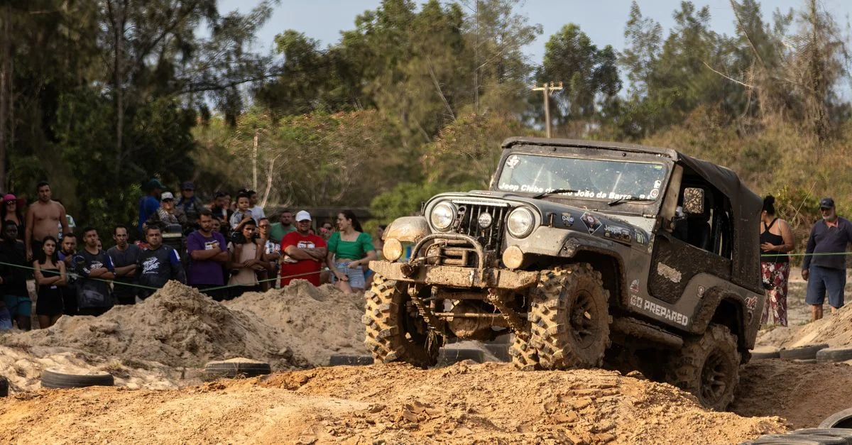 Un jeep tout-terrain affronte un parcours boueux avec une foule de spectateurs acclamant en plein air.