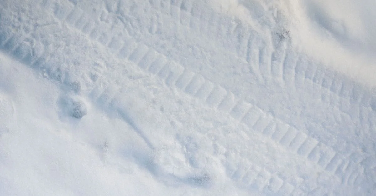 Gros plan sur des traces de pneus imprimées dans la neige, capturant la texture et le motif des routes hivernales.