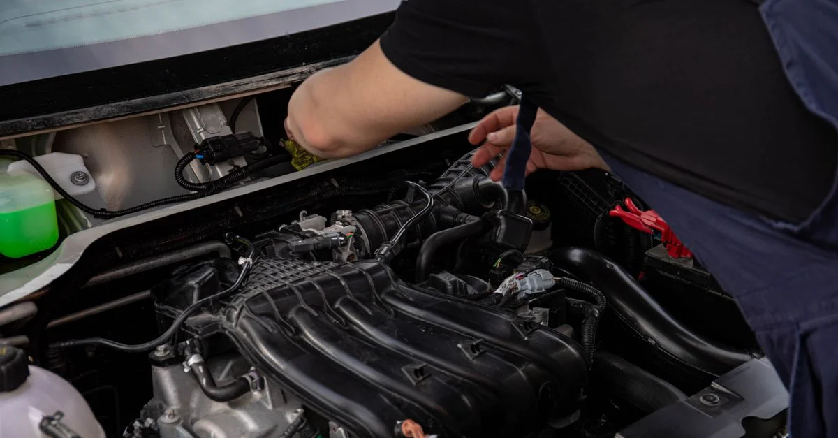 Gros plan sur un mécanicien travaillant sur un moteur de voiture. Idéal pour des thèmes de maintenance et de réparation automobile.