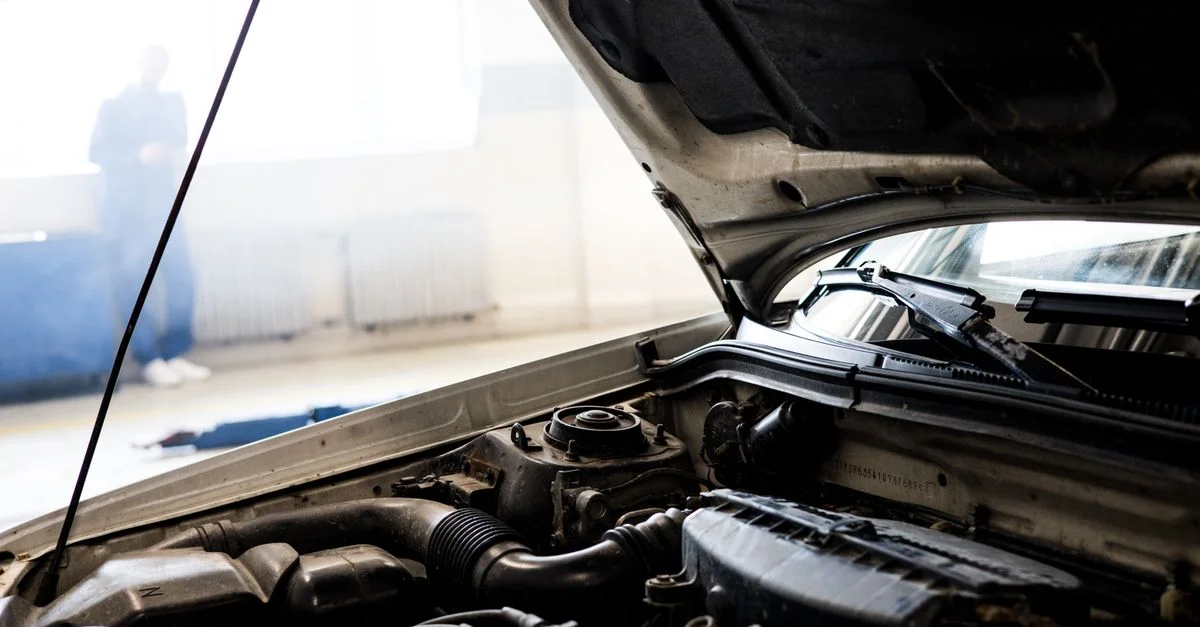 Image détaillée d'un moteur de voiture sous le capot ouvert dans un garage intérieur bien éclairé.