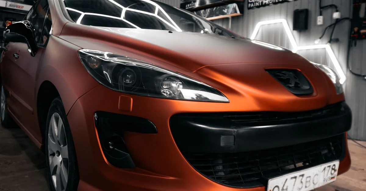 Voiture élégante orange mat exposée dans un atelier automobile contemporain éclairé au néon.