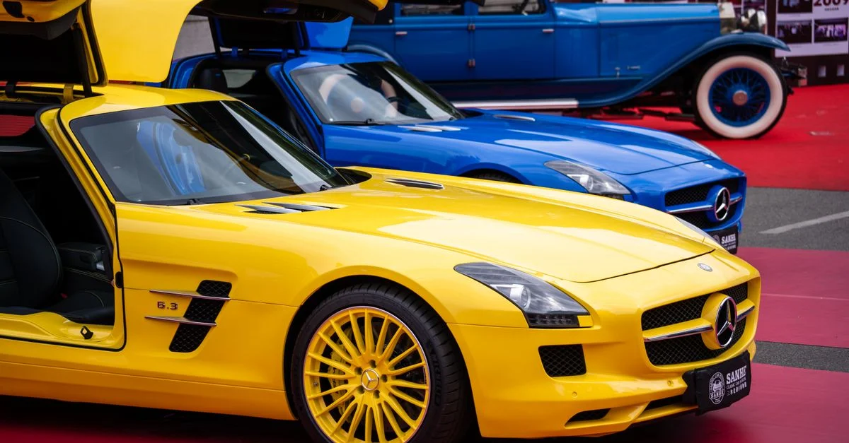 Gros plan d'une voiture de luxe jaune vif exposée lors d'un salon de l'automobile, mettant en avant un design élégant et des portes ouvertes.