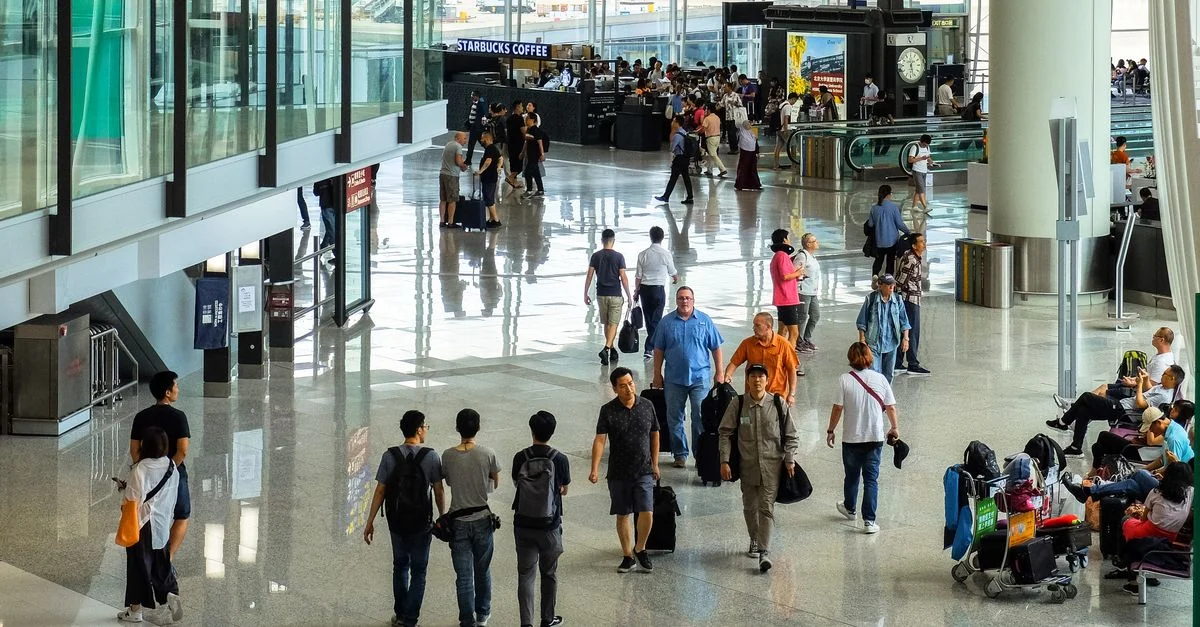 Passagers marchant et assis dans un terminal d'aéroport animé à Hong Kong.