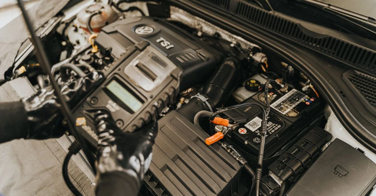 Vue en gros plan d'un mécanicien diagnostiquant un moteur Volkswagen avec des équipements spécialisés.