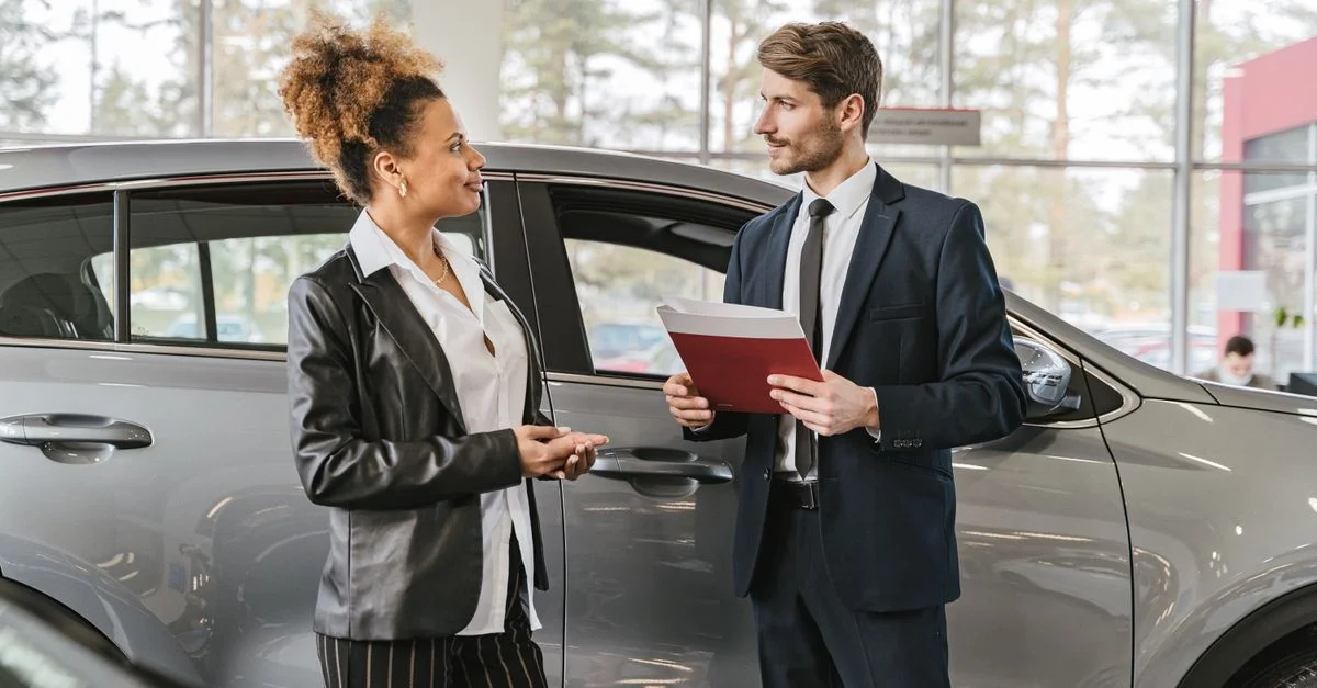 Une femme discutant d'achat de voiture avec un concessionnaire dans un showroom de concession automobile.