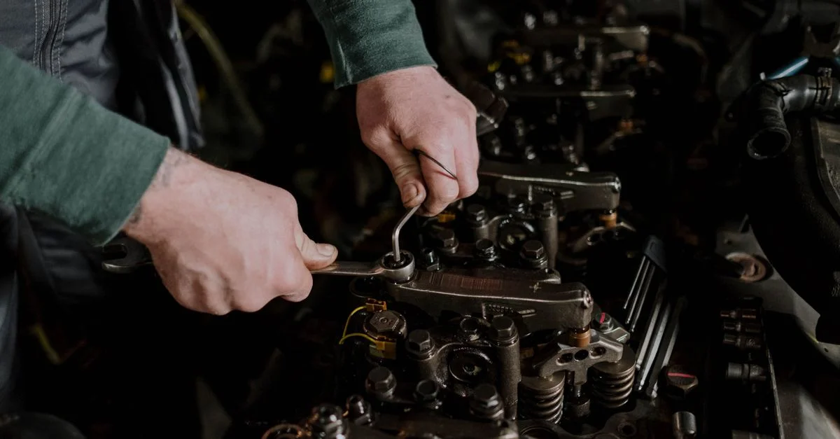 Gros plan sur un mécanicien utilisant des outils à main pour réparer un moteur, mettant en valeur la précision et l'habileté.