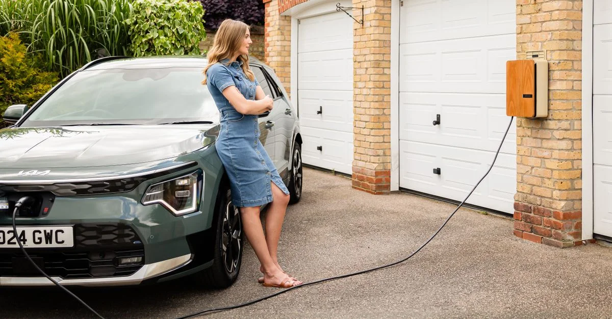 Femme rechargeant un véhicule électrique à domicile avec une borne de recharge murale moderne.