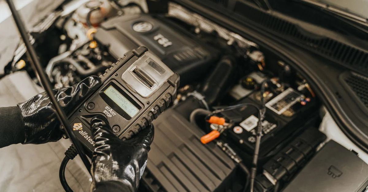 Mécanicien diagnostiquant un moteur de voiture avec un outil de diagnostic, mettant en avant son expertise technique et son soin automobile.
