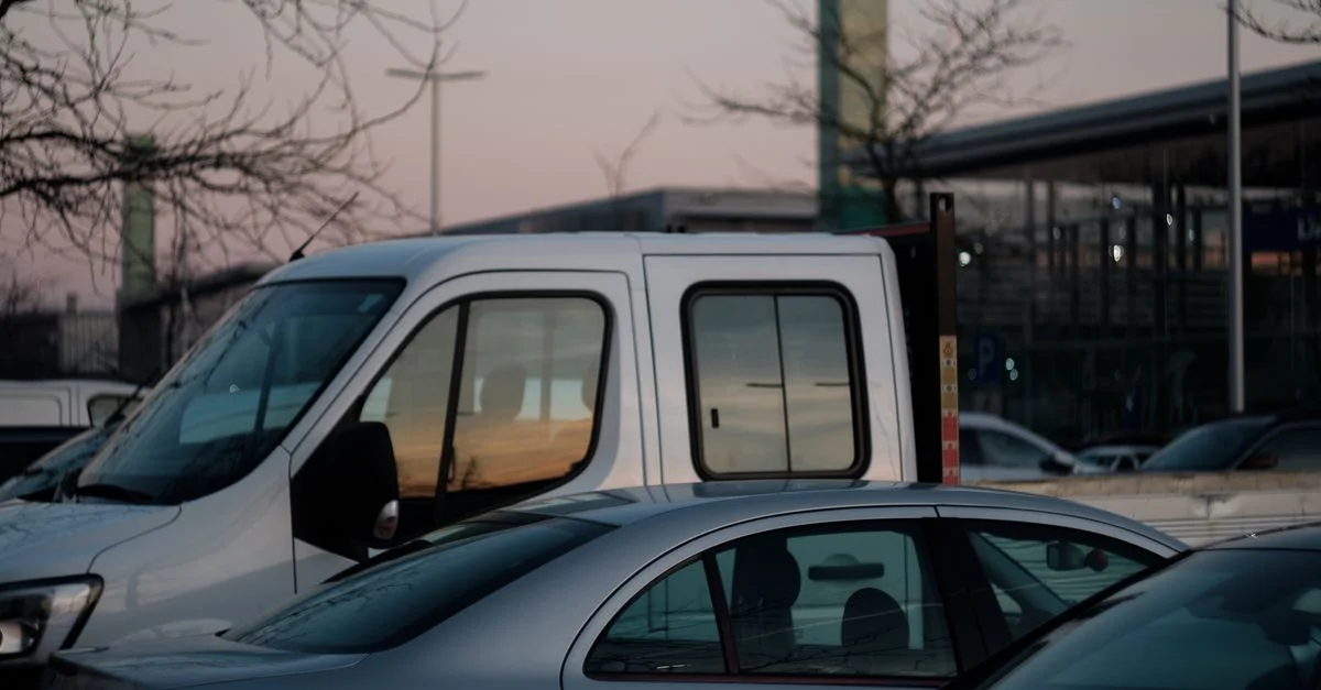 Scène urbaine mettant en scène des véhicules stationnés au crépuscule, mettant en valeur la vie urbaine et les transports.