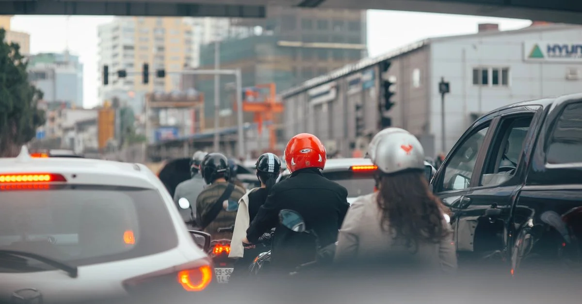 Vue de rue de la ville remplie de voitures et de motocyclistes attendant aux feux de circulation.