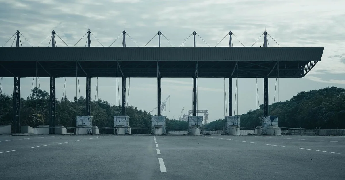 Péage vide sur une autoroute déserte avec un ciel couvert et une végétation environnante.