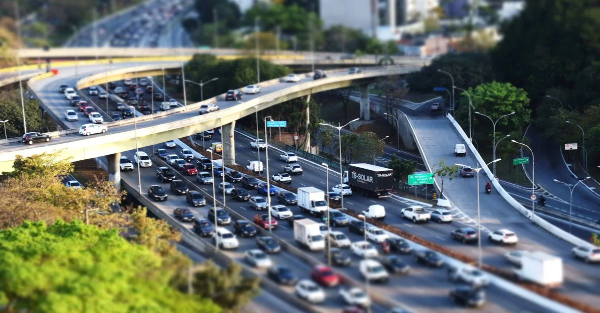 Trafic dense sur une autoroute urbaine à plusieurs niveaux avec effet tilt-shift, mettant en valeur un système de transport complexe.